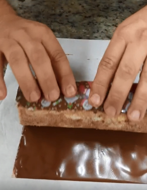 Enrolando o rocambole na folha de transfer com chocolate